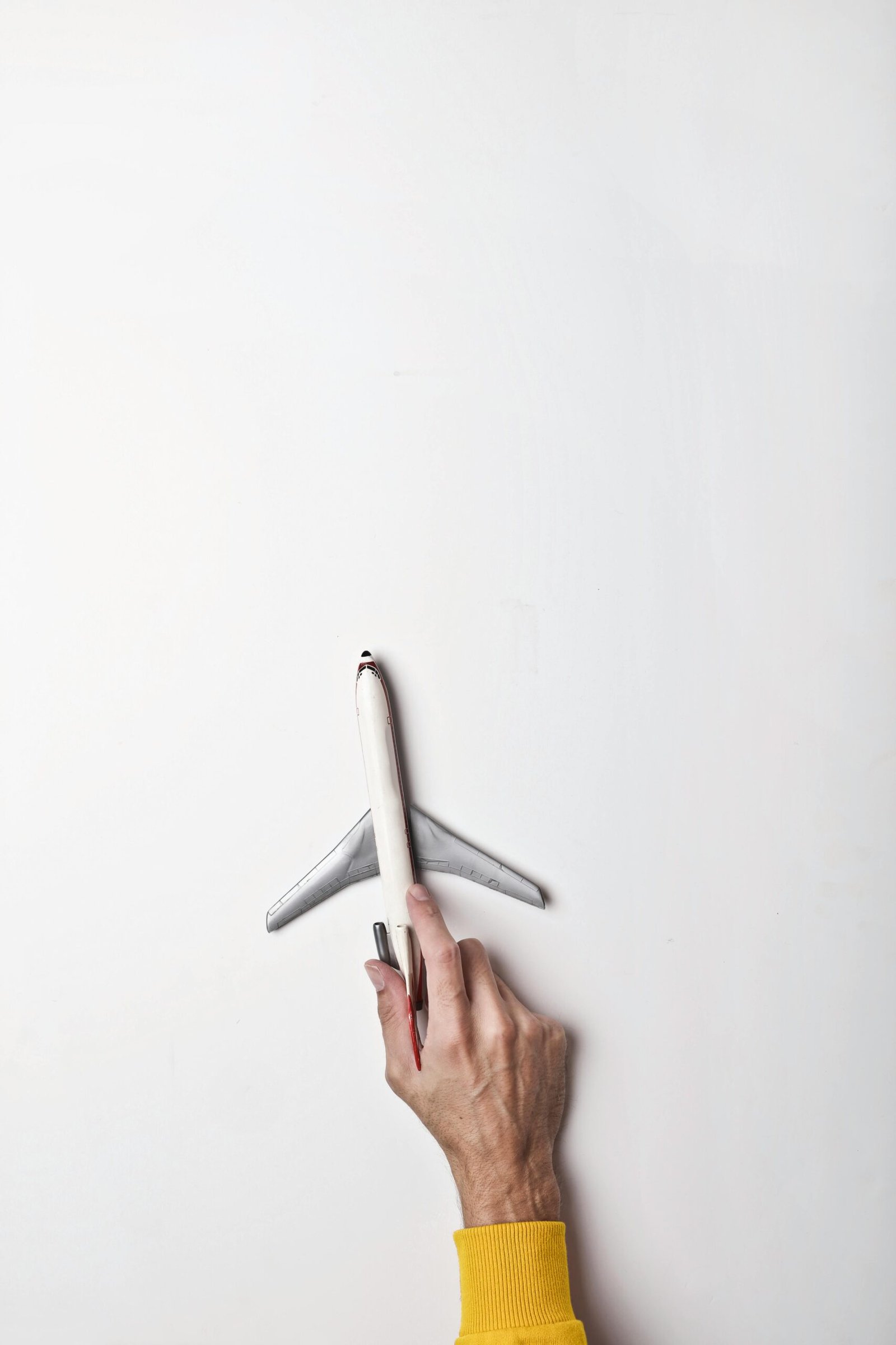 Top view of crop male holding tail of toy model airplane on white background in studio